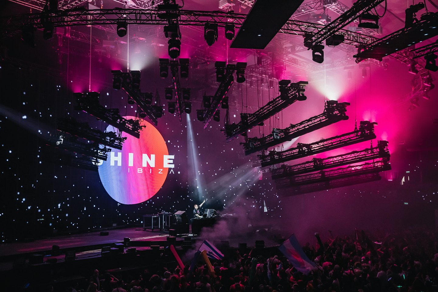 DJ performing on stage in front of a large crowd.